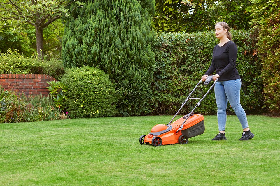 A woman mowing a lawn using a Flymo® wheeled lawnmower.