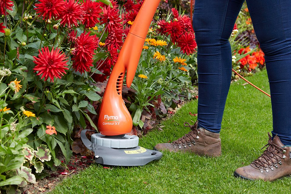 A person using a Flymo® grass trimmer to trim the lawn edges.