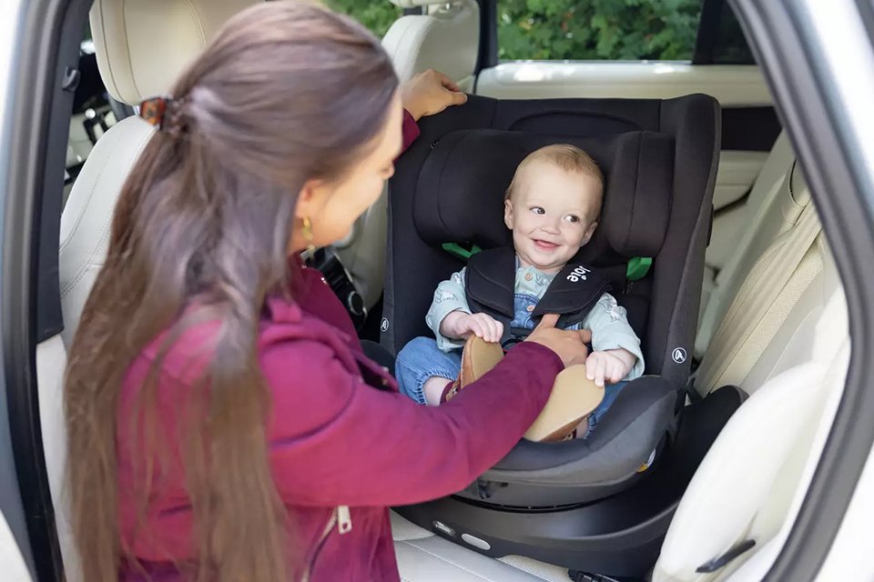 A child sitting in a Joie i-Pivot Grow Spinning Birth To Booster Car Seat.