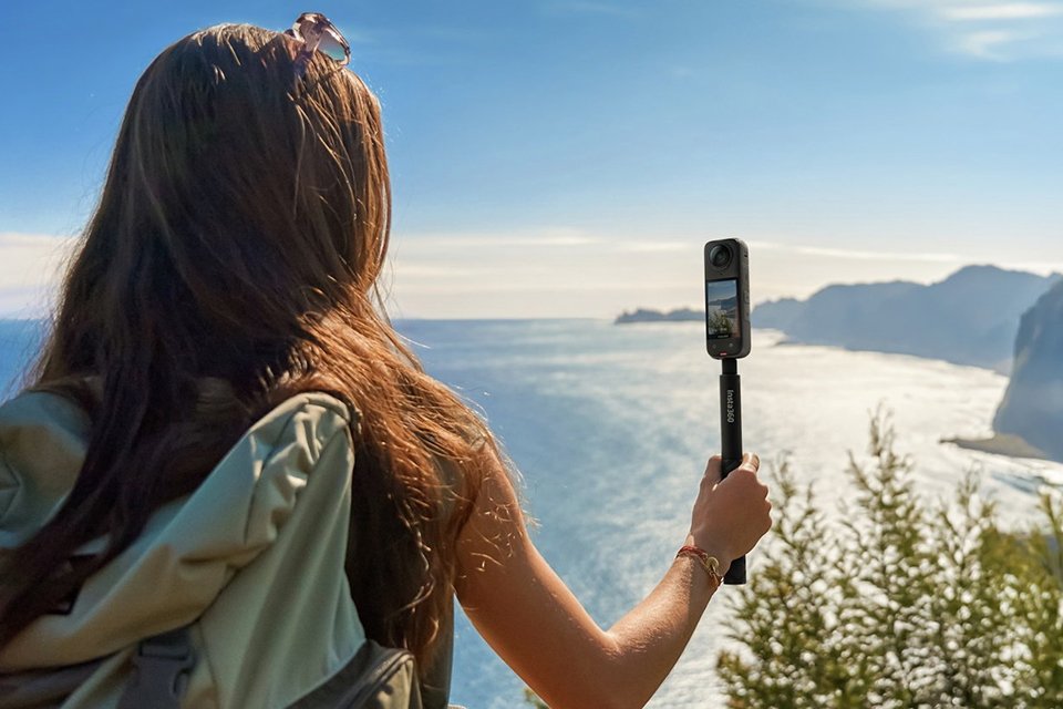 A woman using an Insta360 X4 action camera to shoot a travel video.
