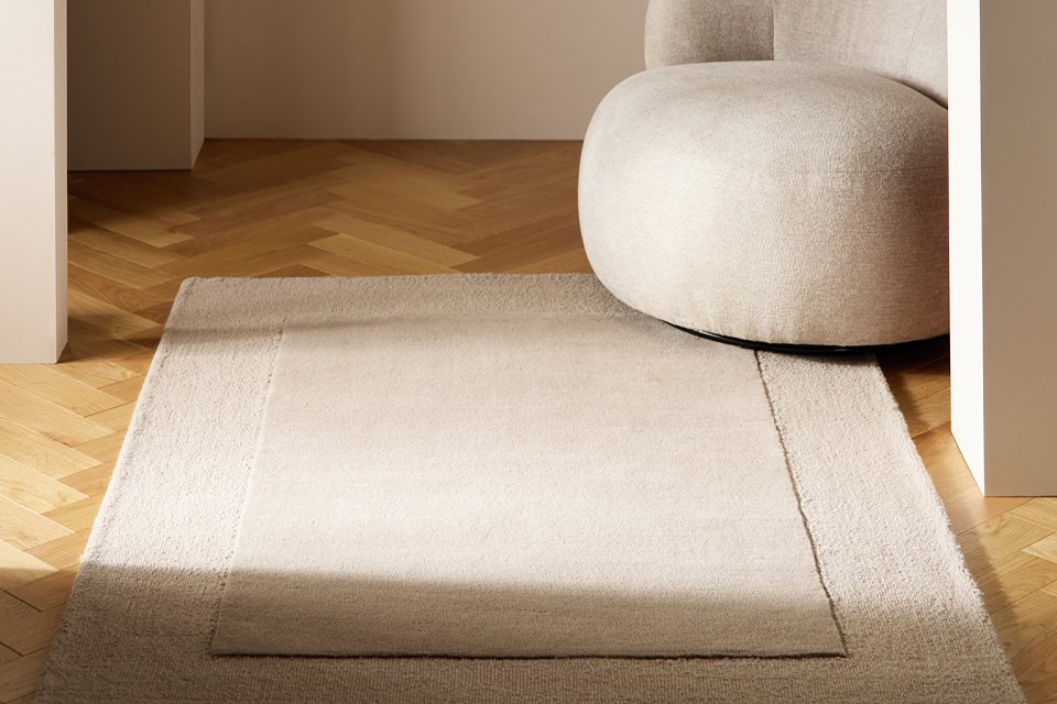 Habitat Simple Border Taupe Wool Cut Pile rug with an arm chair placed in a living room.