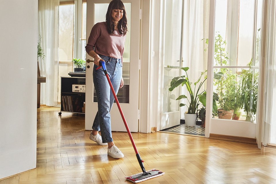 A woman using a Vileda 1-2 Spray Mop to clean her floor.