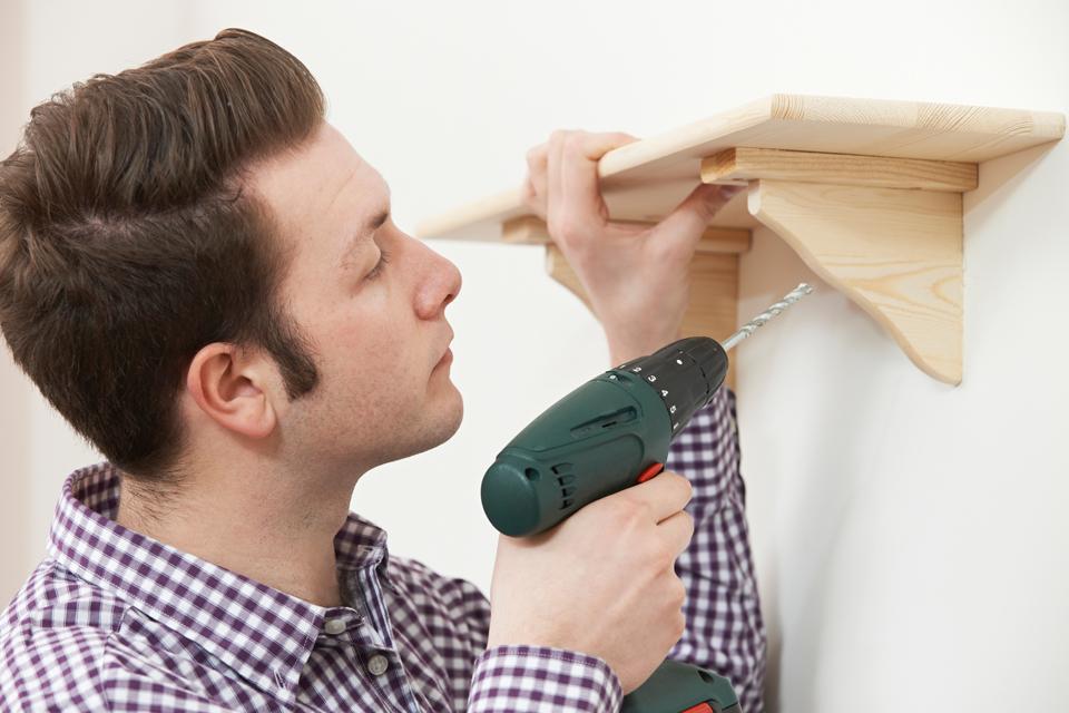 Man drilling a hole to fit a shelf.