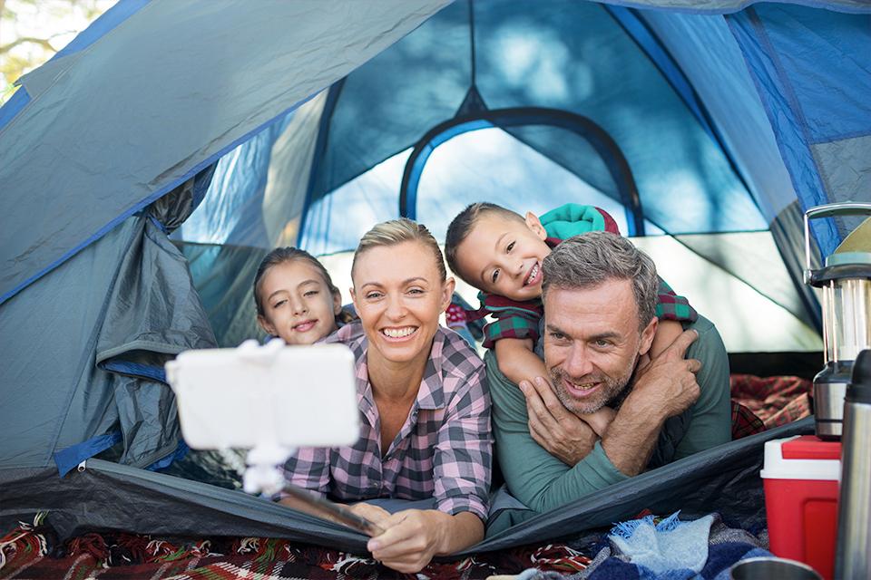 Smiling family taking selfie in the tent.
