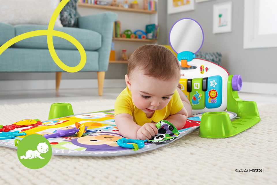 A baby playing with a Fisher-Price Kick 'n' Play Piano Baby Gym toy.