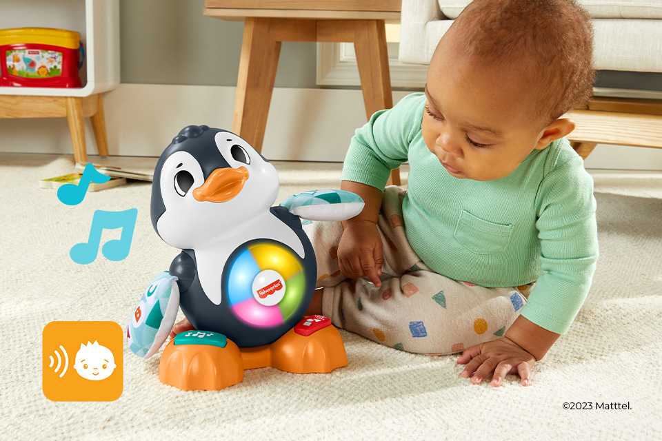 A baby playing with a Fisher-Price Linkimals Cool Beats Penguin musical toy.