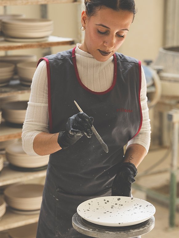 A woman painting a plate from Habitat Jackson dinnerware set in a factory.