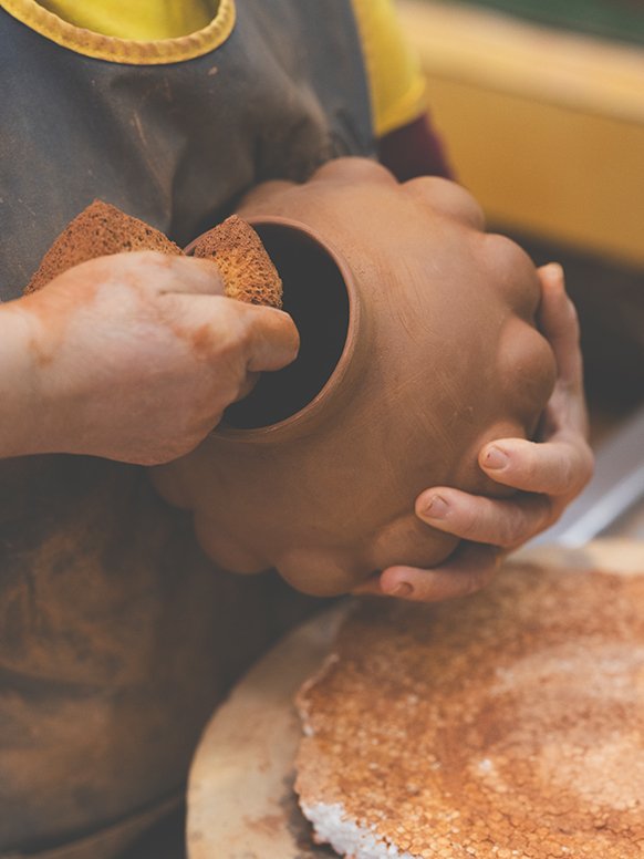 A person working on a Habitat terracotta vase in a factory. 