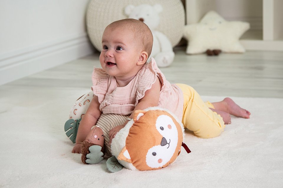 A baby playing with a Red Kite Tummy Time Woodland Walk roller.