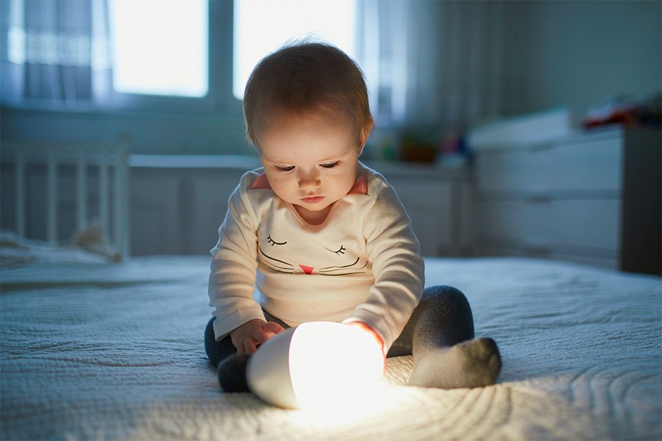 A baby playing with a glowing nightlight.