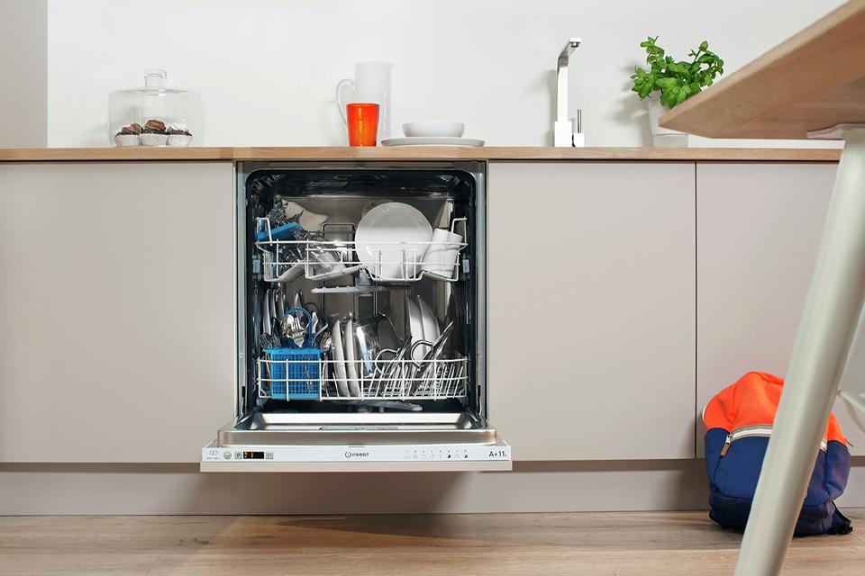 An open, integrated dishwasher, full of clean dishes.