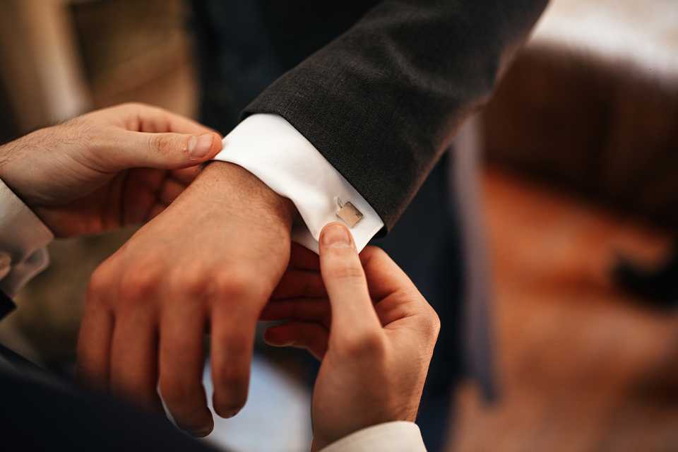 A man helps straightening the cuffs of another man's sleeve after putting on the cufflinks.