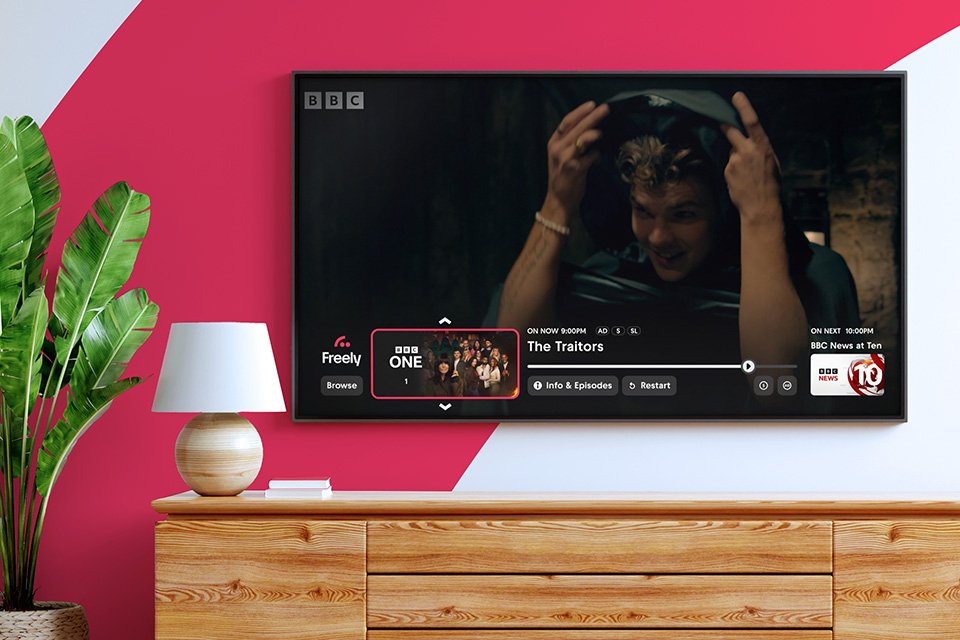 A TV show being watched via the Freely platform on a smart TV in a living room setup.