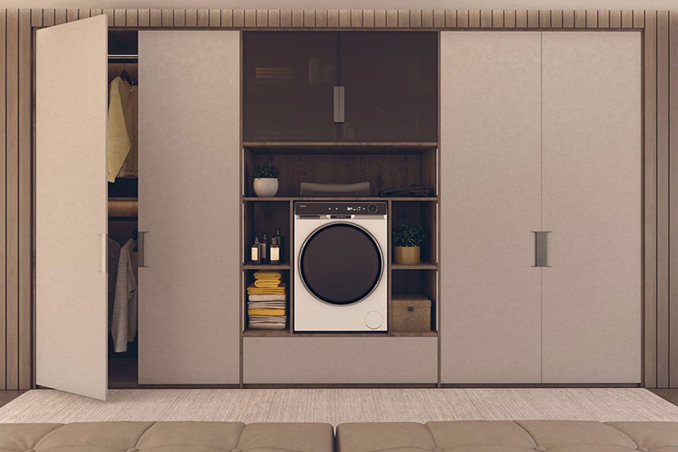 A white Haier washing machine with some clothes on a rack on either side.