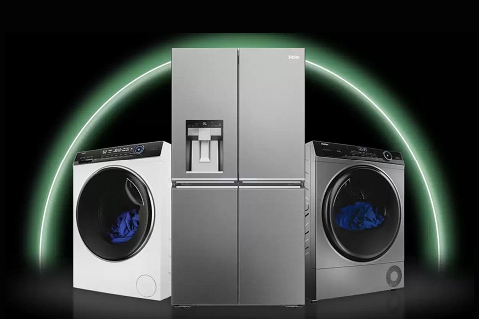 Two Haier washing machines and a fridge freezer against a black background.