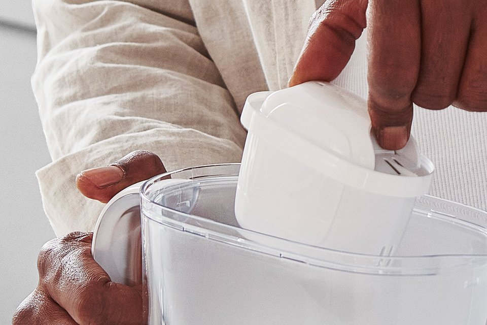 A person inserting a BRITA water filter cartridge into a BRITA jug. 