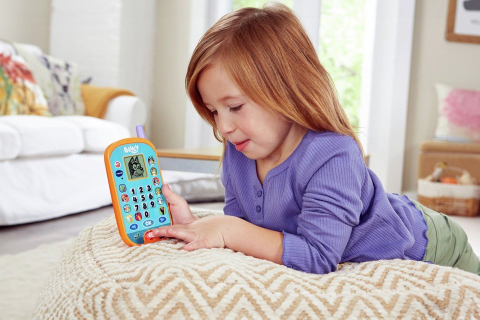 A girl playing with a Vtech Bluey Ring Ring phone.