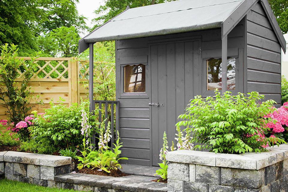 A steel smoke coloured shed in a garden.