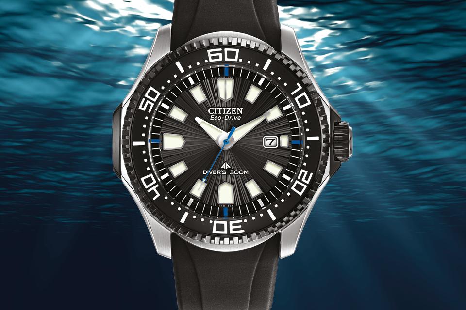 Image shows a Citizen Divers watch with a black sillicone strap against a deep sea background.