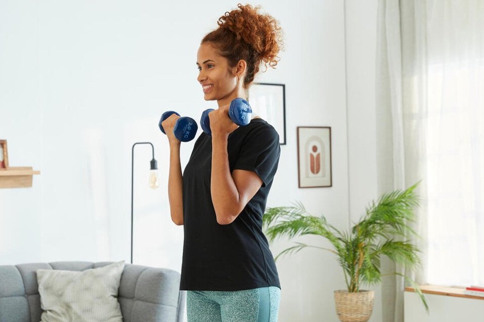 A woman using a Decathlon PVC 2 x 2kg dumbbells set.