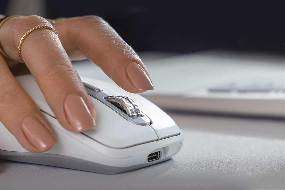 A woman using a Logitech MX Anywhere 3S wireless mouse to scroll on her laptop.