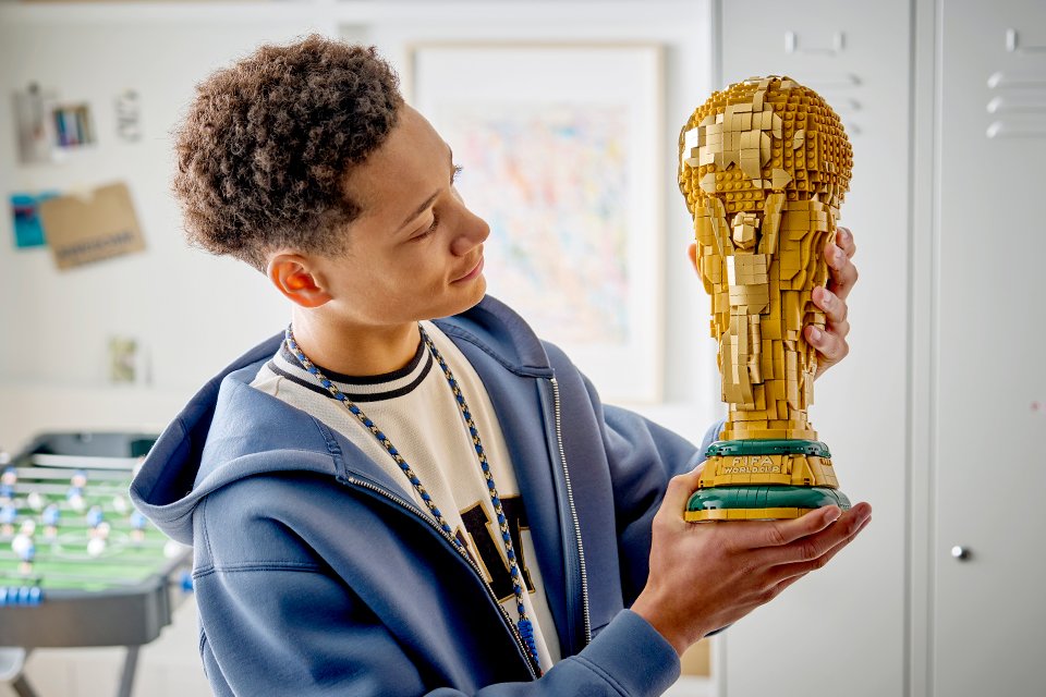 Man holding and admiring the LEGO® Editions FIFA World Cup Official Trophy set. 