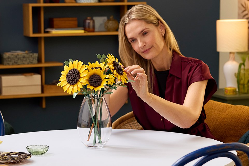 Woman admiring the LEGO® Botanicals Sunflower Bouquet set.