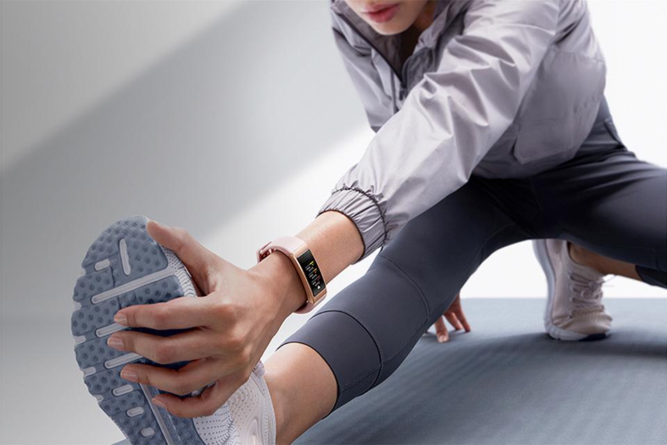 A lady stretches whilst wearing a Huawei Band 4 Pro.