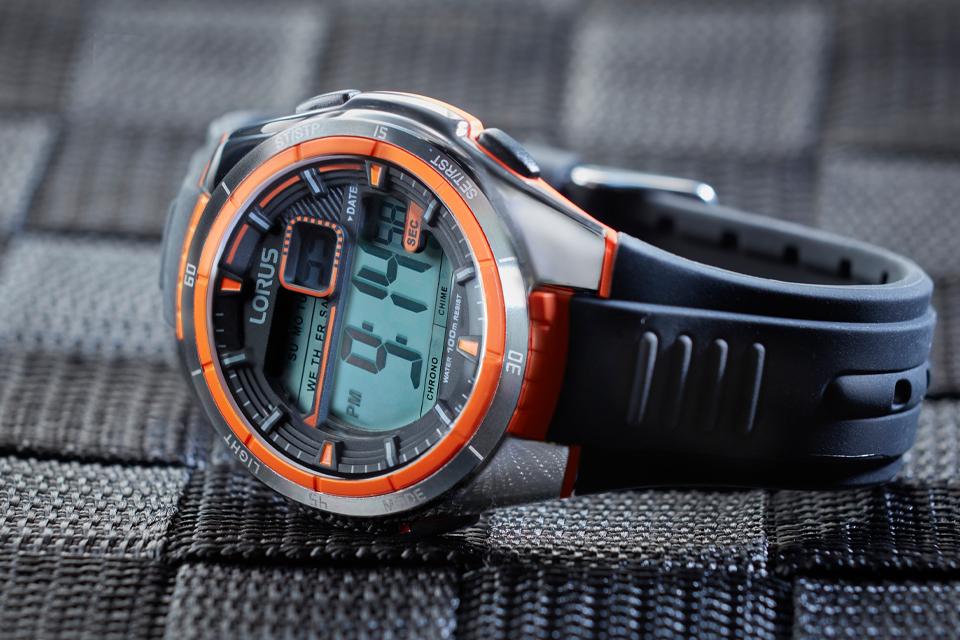 A digital Lorus watch with a colourful plastic strap is placed on its side atop an outdoorsy woven fabric.
