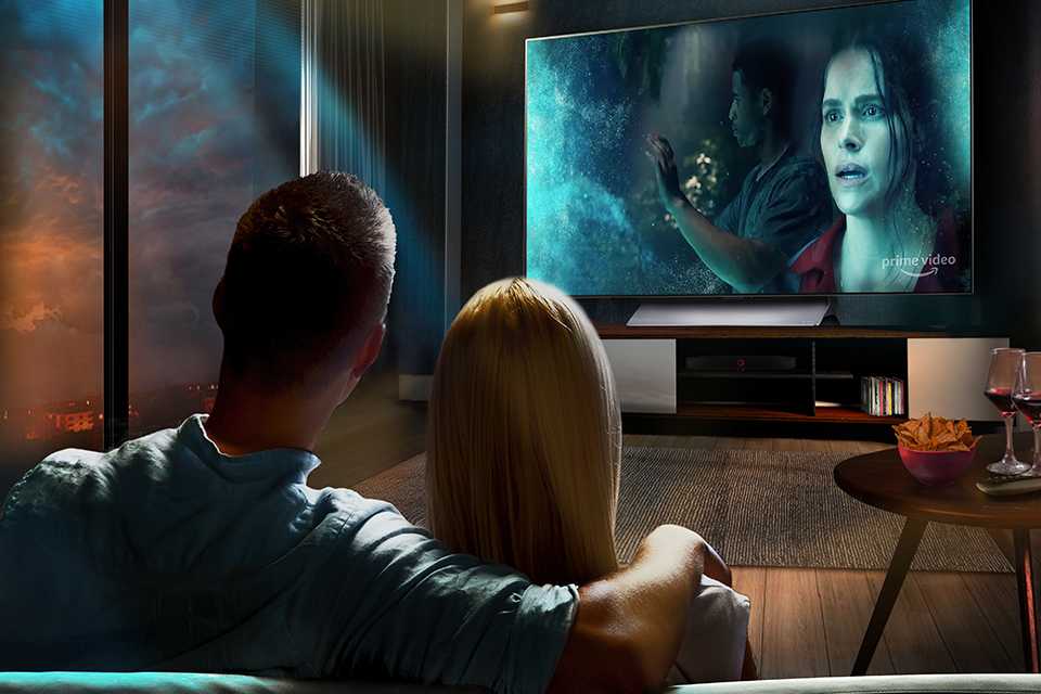 A couple watching a movie on an LG OLED TV in a living room.