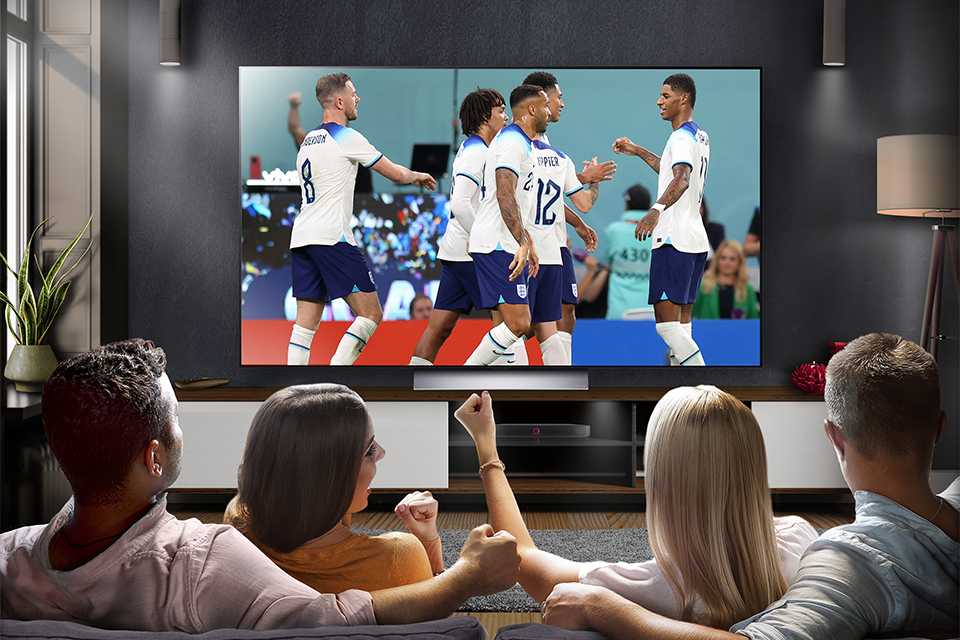 A group of four people watching football on an LG OLED tv.