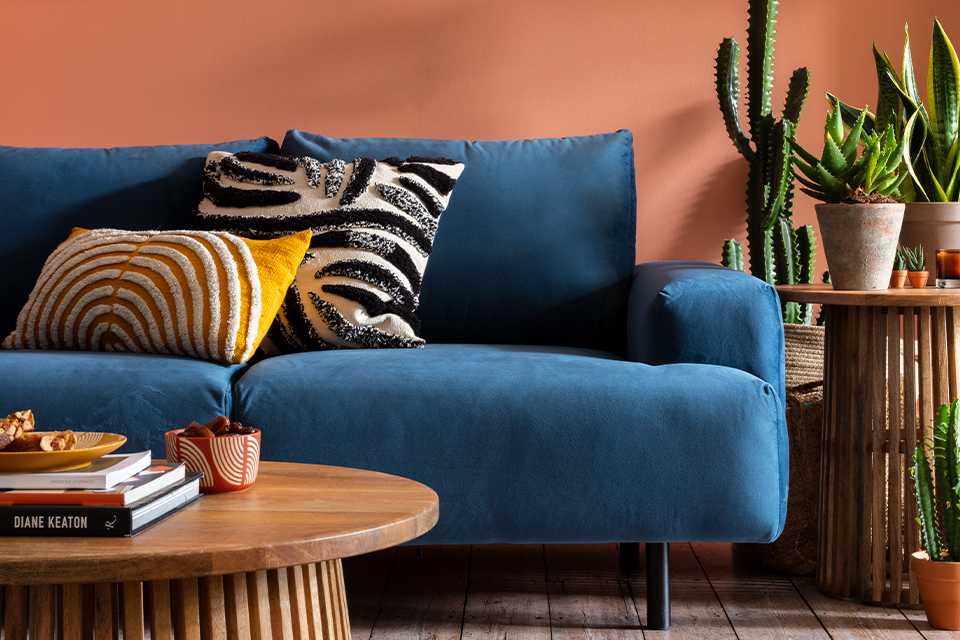 Blue soft sofa against orange living room wall.
