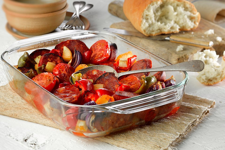 A Pyrex Irresistible 3 piece glass roaster set with food inside.