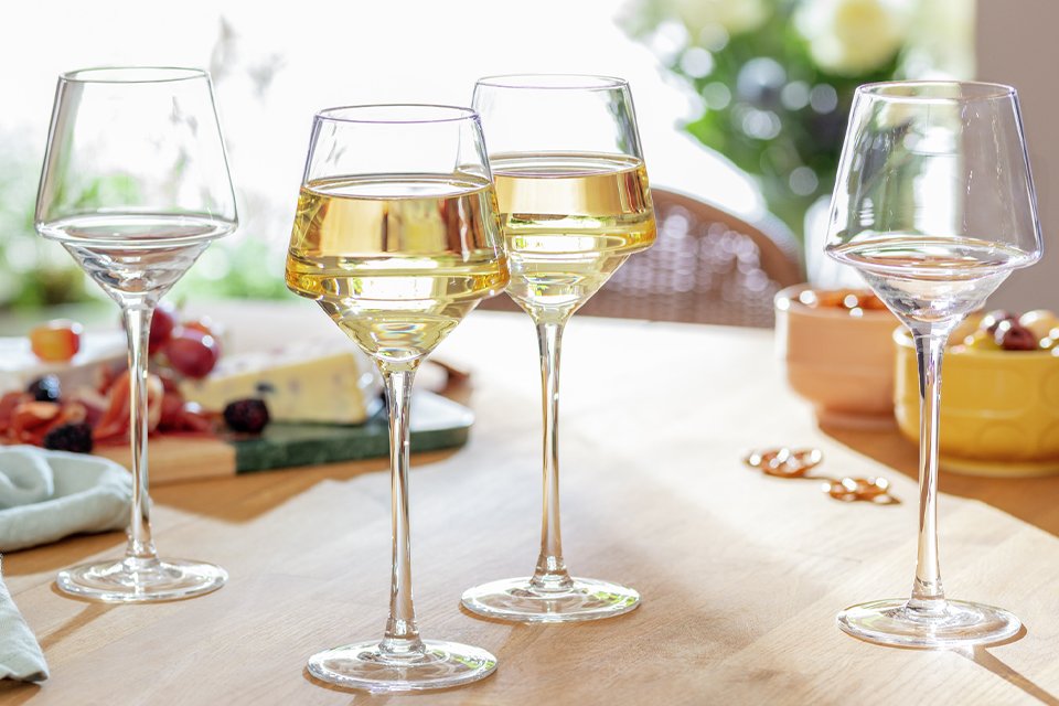 Habitat Sahara set of 4 wine glasses on a table with some cheese and nuts.