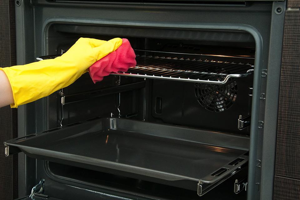 Someone cleaning the inside of an oven with a sponge.