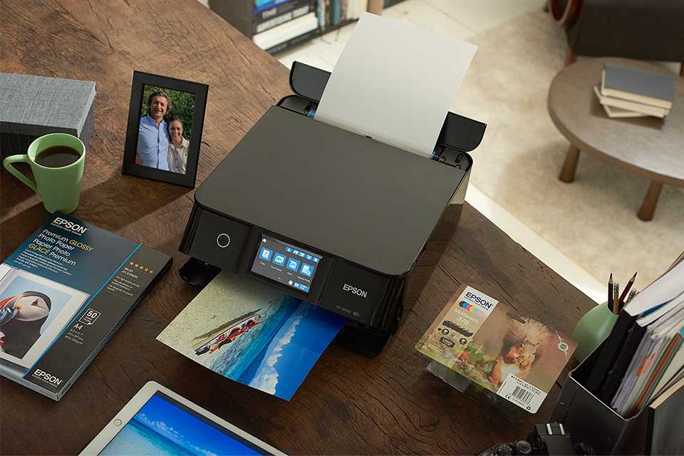 Epson home printer, with a colourful photo print sliding out on Epson paper.
