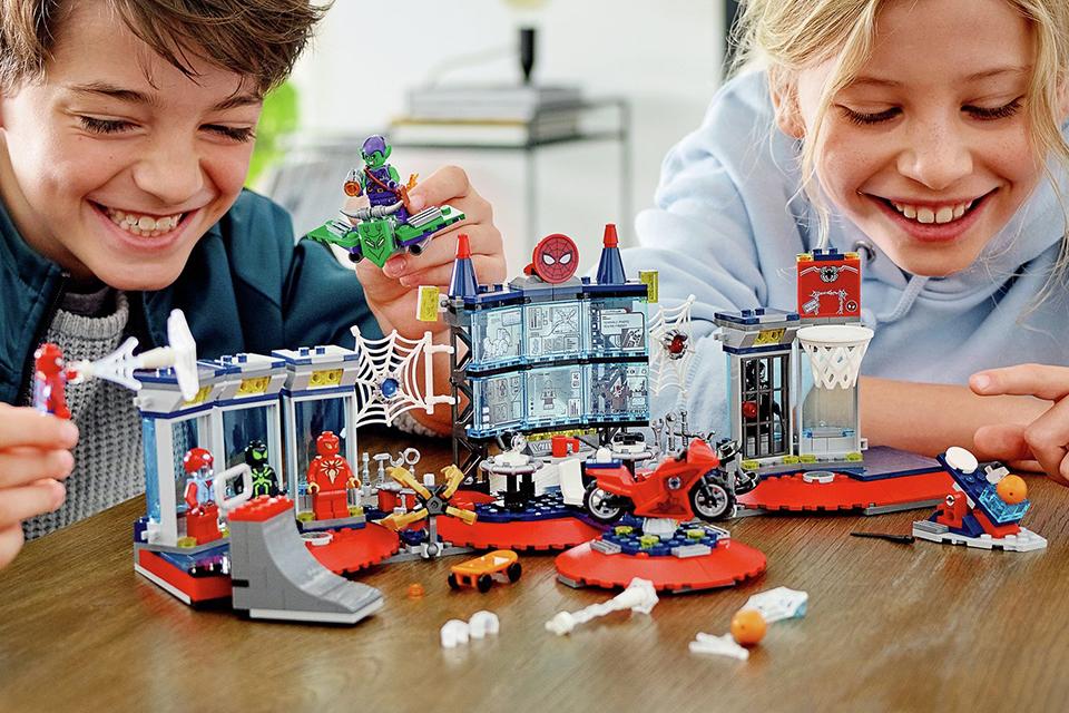 A boy and girl playing with the LEGO® Marvel Spider-Man Attack on the Spider Lair Set.