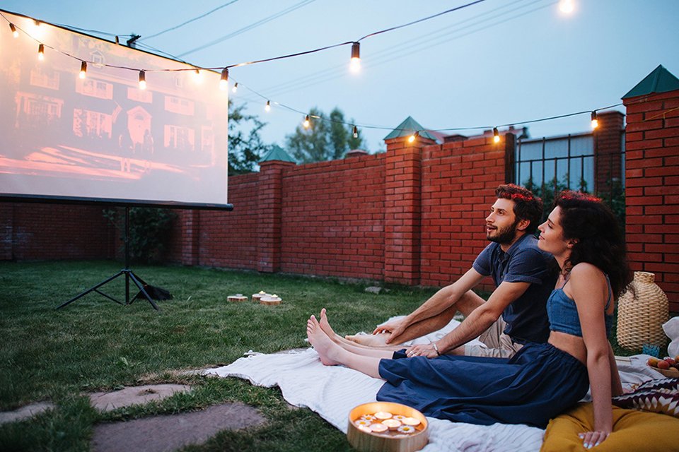 A couple sat in a garden watching a film on a projector.