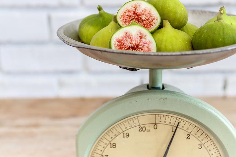 An image of kitchen scales with figs.