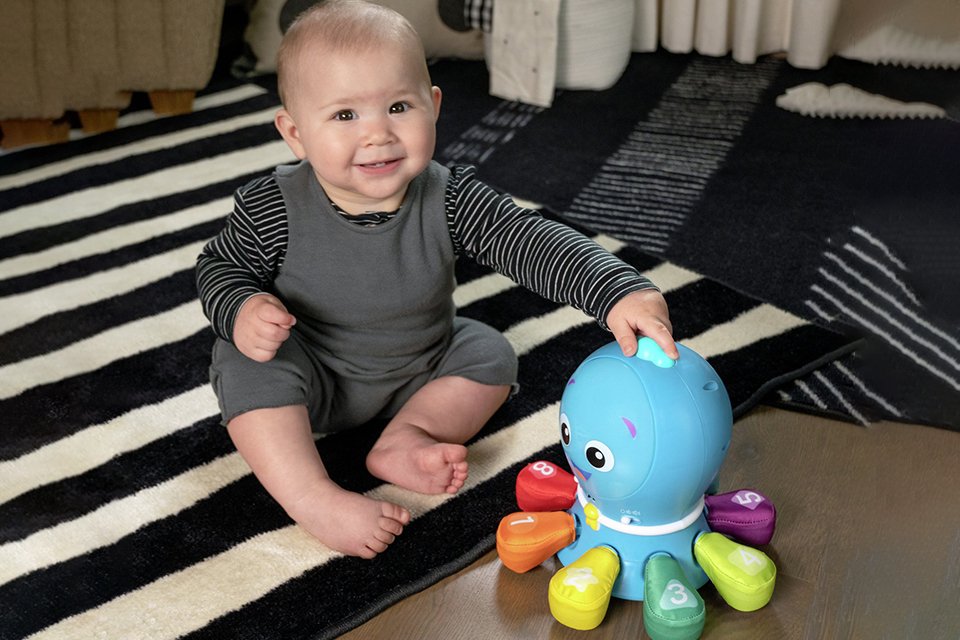 A baby playing with a colourful octopus.