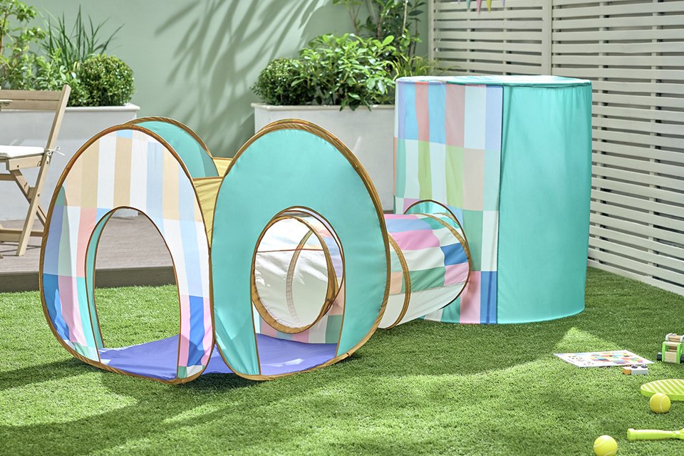 A boy playing in a Chad Valley 3-in-1 Play Tent in the garden.