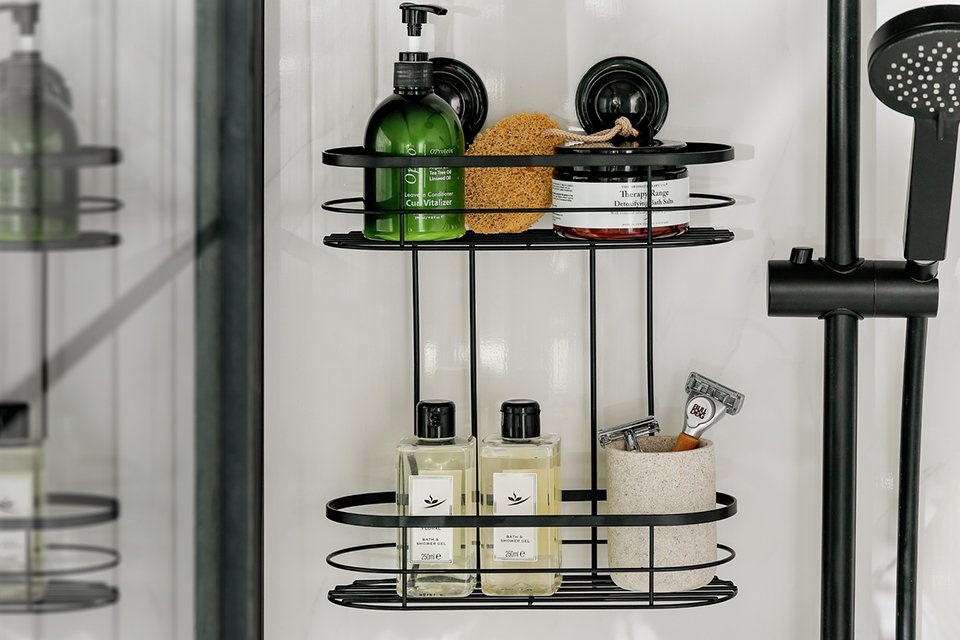 A 2 tier black shower caddy wall mounted in the shower.