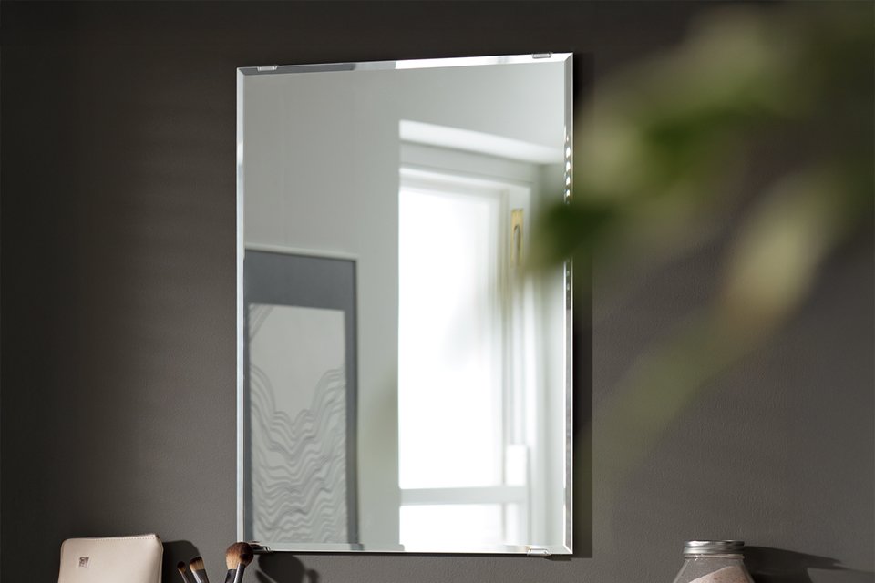 A rechtangular mirror in a bathroom.