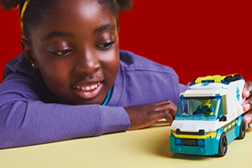 Girl playing with a LEGO® City ambulance toy.