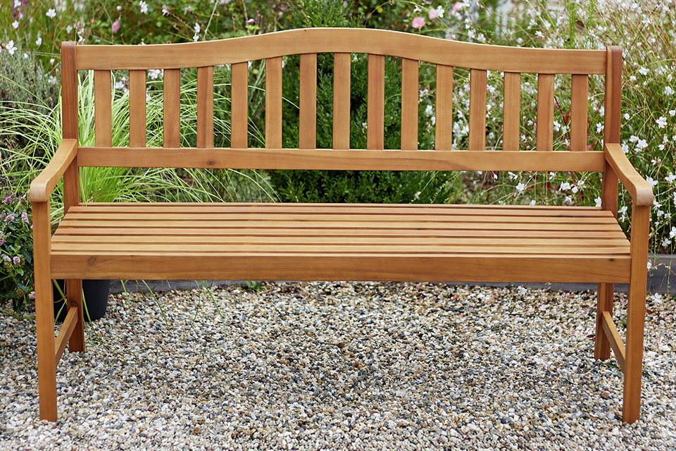 An Argos Home 3 seater wooden garden bench placed outdoors.