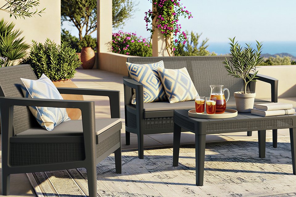 A grey Keter resin lounge set placed outdoors with cushions on top of it.