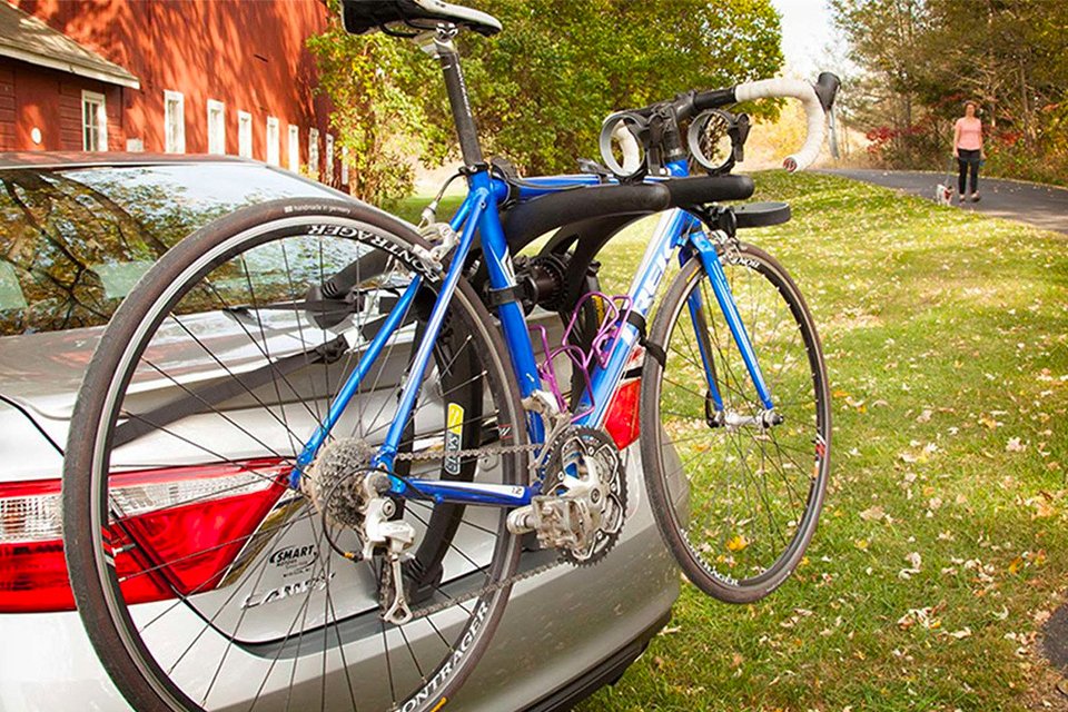 A bike on a bike rack behind the car.