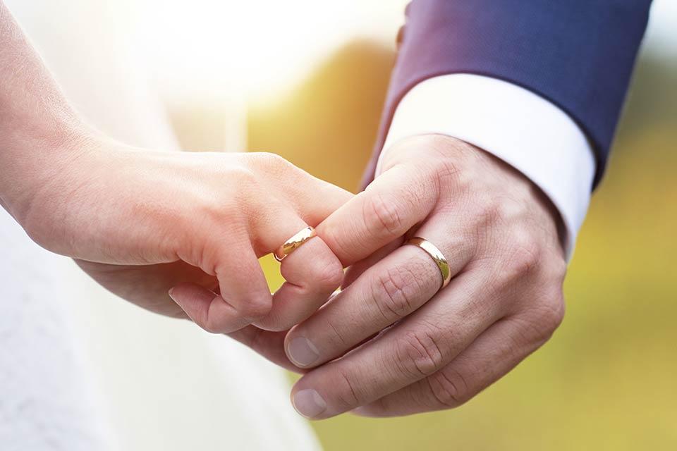 A couple holding hands wearing two wedding rings.