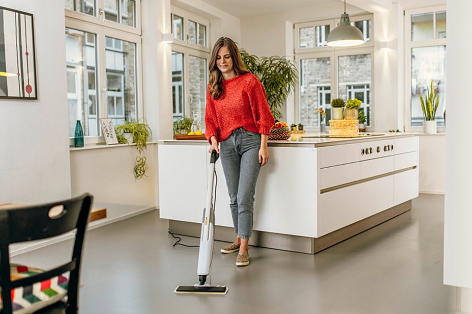 A woman using Kärcher steam cleaner on her kitchen floor.