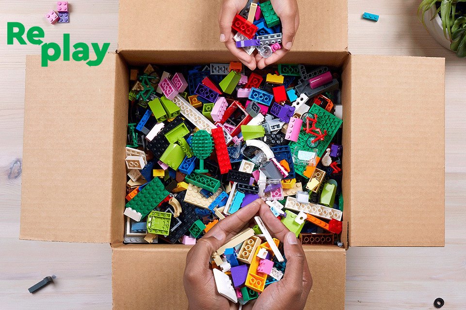 Two people taking handfuls of LEGO bricks from a box.
